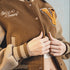 Brown varsity jacket with embroidered text and patches, featuring the brand 'Maden Clothing'.